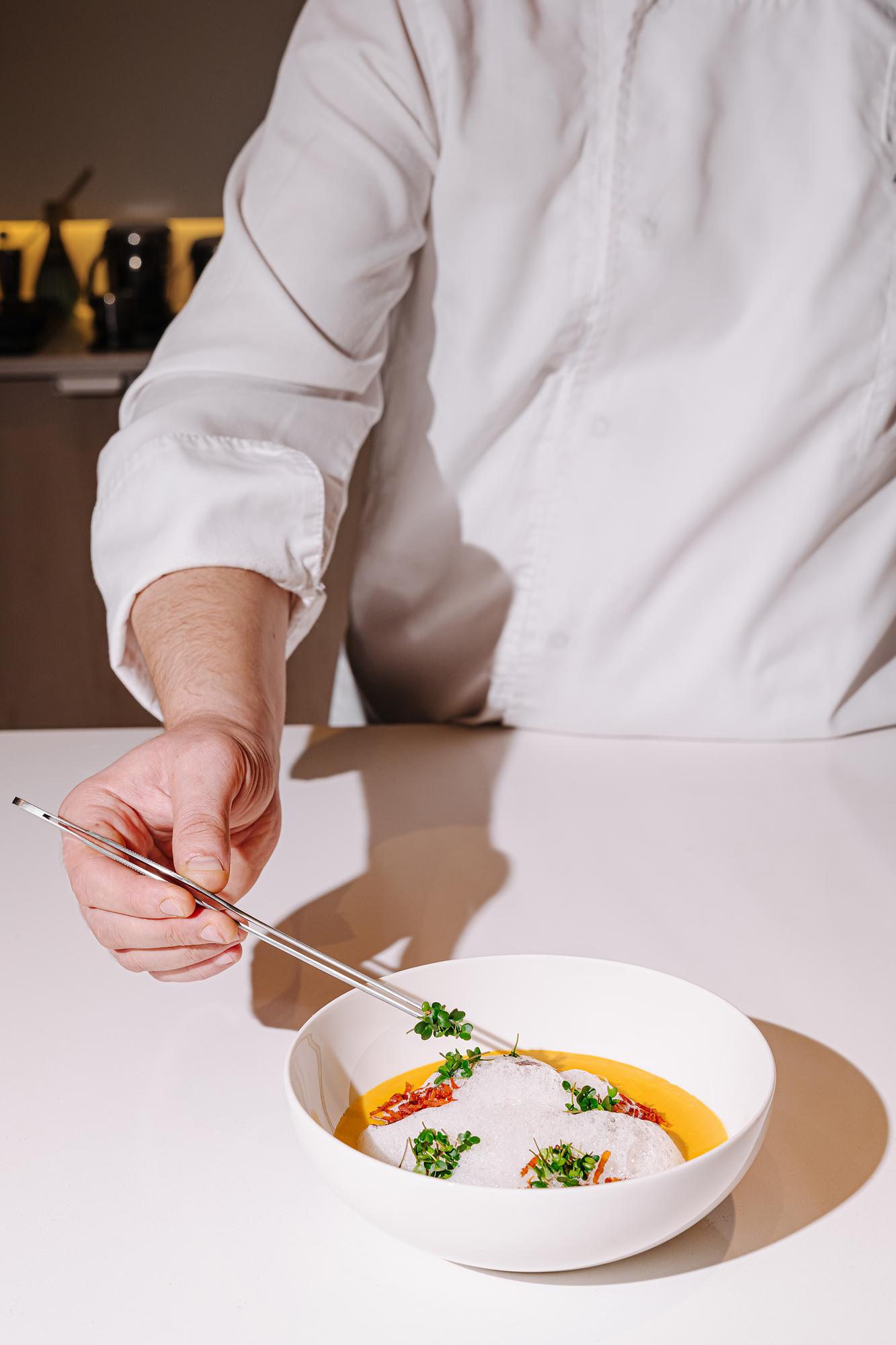 Chef arranging plated dish in a warm kitchen